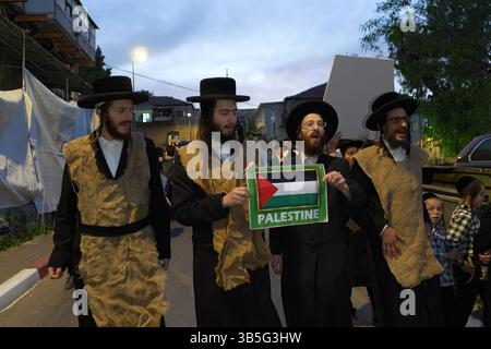 I membri di Neturei Karta, un movimento ebraico ultra-ortodosso periferico all'interno del blocco anti-sionista che indossa una borsa di iuta per significare dolore, hanno una bandiera palestinese mentre camminano attraverso il quartiere religioso di Mea Shearim in una manifestazione contro la creazione dello stato di Israele durante il 77° giorno dell'indipendenza di Israele il 1° maggio 2025 a Gerusalemme. Neturei Karta si oppone al sionismo e chiede uno "smantellamento pacifico" dello Stato di Israele, nella convinzione che agli ebrei sia proibito avere un proprio stato fino all'arrivo del Messia ebraico e che lo Stato di Israele sia una ribellione contro Dio. Foto Stock