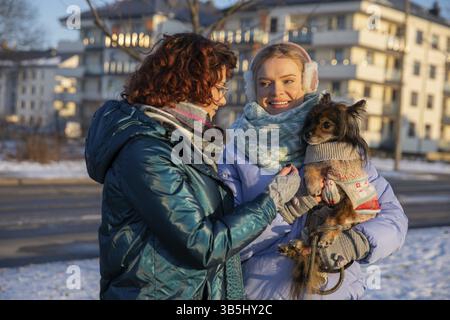 Silhouette di due donne viste dalla vita verso l'alto. Le donne parlano e sorridono. Sono vestiti con abiti caldi come la neve giace. Uno dei guerrieri Foto Stock
