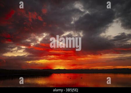 Un tramonto mozzafiato caratterizzato da tonalità vibranti che si riflettono splendidamente sulle acque calme, ideale per temi tranquilli Foto Stock