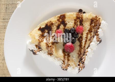 Fresche, golden pancake con frutta e crema su una piastra bianca con sfondo sfocato Foto Stock