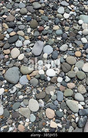 Primo piano di ciottoli colorati e lisci su una spiaggia. Struttura naturale e sfondo in pietra, nessuna gente, dettagli astratti sulla costa. Foto Stock