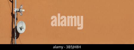 Due antenne di telecomunicazione utilizzate per la rete cellulare e Internet wireless, fissate alla parete dell'edificio. Ricezione e digitalizzazione di più pezzi Foto Stock