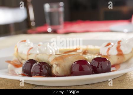 I pancake freschi con cherry disposti sul tavolo in legno Foto Stock