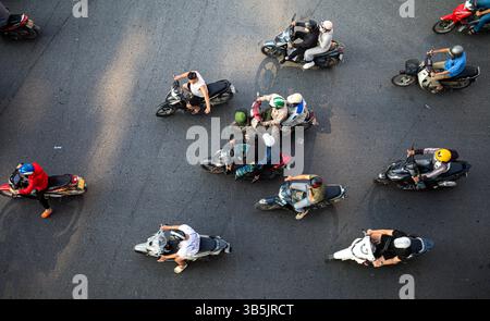 Guardando direttamente dall'alto verso i motociclisti su una strada nel centro di Hanoi, Vietnam. Foto Stock