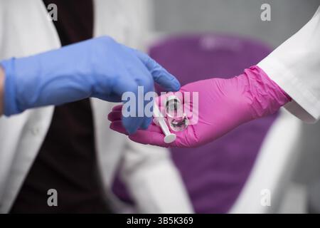 Tiene in mano un flaconcino con una medicina e una siringa e lo dà a uno stagista medico in modo che possa conoscere questo set per la produzione di vaccini e. Foto Stock