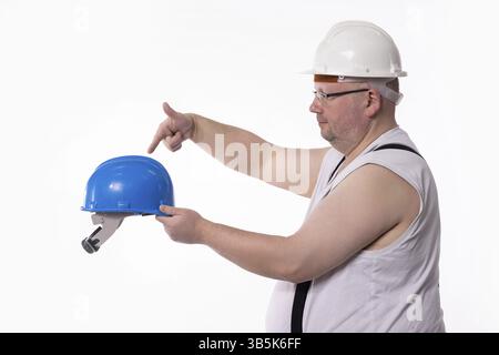 Un operaio edile indossa caschi di sicurezza, dimostrando l'attrezzatura corretta e dimostrando consapevolezza della sicurezza Foto Stock