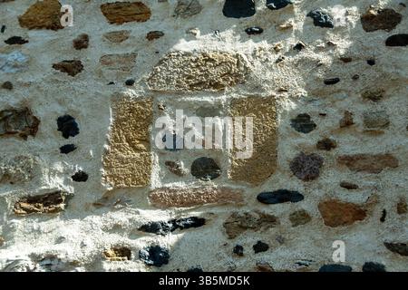 Un muro di pietra intemprata mostra un motivo distinto fatto di varie pietre e Malta, che riflette l'artigianato di un'epoca passata. Francia Foto Stock