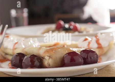 I pancake freschi con cherry disposti sul tavolo in legno Foto Stock