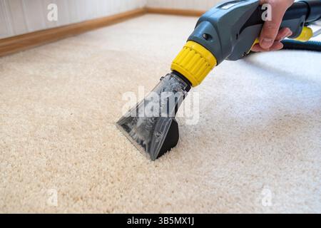 Pulizia di tappeti con aspirapolvere tenuto da un maschio adulto. Foto Stock