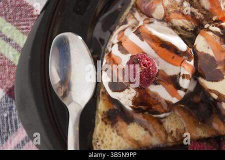 Fresche, golden pancake con frutta e crema su una piastra nera con sfondo sfocato Foto Stock
