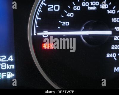 Primo piano del cruscotto automobilistico che rivela la spia luminosa del freno di stazionamento che segnala l'innesto dell'impianto frenante sul quadro strumenti del veicolo Foto Stock