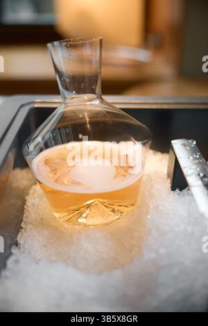Lo champagne rosa viene raffreddato in una nicchia con ghiaccio nel ristorante, illuminazione locale, armadietto dei vini, bollicine Foto Stock