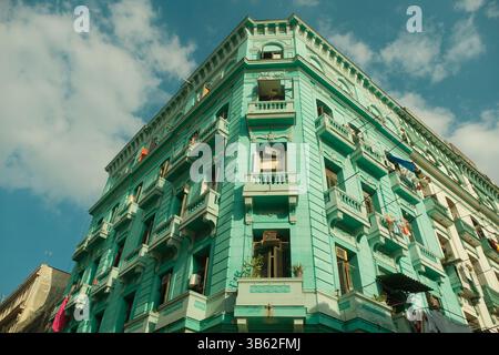 Basso angolo di un alto edificio turchese in stile coloniale a l'Avana Vecchia, Cuba, con balconi e splendidi dettagli architettonici, sul sole luminoso Foto Stock