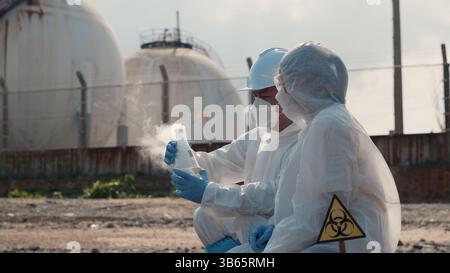 Ecologo di campionamento acqua sostanze chimiche tossiche dal fiume con provetta in vetro e fumo bianco Foto Stock