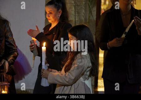 Due donne stanno al lume di candela, una di loro tiene una candela e guarda silenziosamente la luce che crea un'atmosfera contemplativa, Midnight se Foto Stock