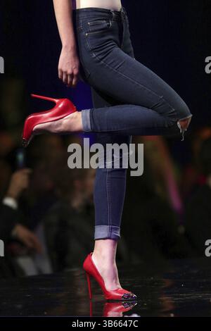 Un modello di passeggiate in pista stylish RED shoes durante una sfilata di moda. Passerella per sfilate di moda evento che mostra la nuova collezione di abbigliamento. Gambe e solo scarpe. Rosso Foto Stock