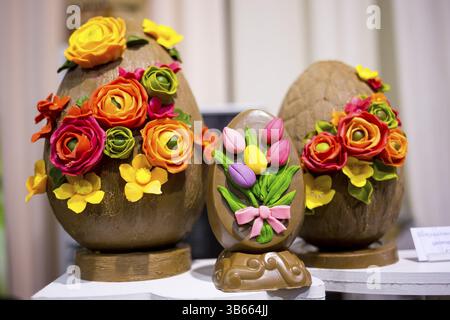 Pasqua uova di cioccolato con fiori fatti a mano da dolci. Tulipani colorati e diversi di rose e fiori di colore giallo. Estremamente gustoso e delizioso dessert Foto Stock