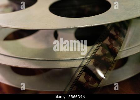 Una collezione di bobine di film metallici impilate insieme, con una bobina che mostra una sezione di film vintage. La scena acquisisce la trama e la cronologia del cine Foto Stock