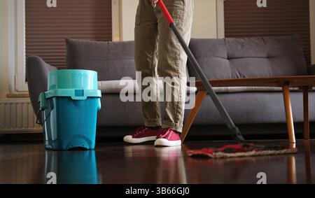 Donna che pulisce il pavimento del soggiorno con mop Foto Stock