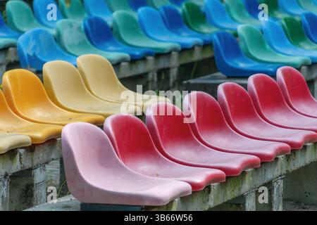Posti a sedere vuoti colorati in file vivaci. Foto Stock