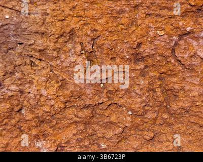 Superficie ruvida rossastra-marrone. Consistenza di roccia rossa incrinata simile a quella di Marte con superficie erosa secca Foto Stock
