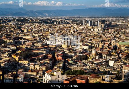 Una vista panoramica di un vasto paesaggio urbano con un mix di architettura storica e moderna, con tetti, cupole e montagne lontane sotto un c Foto Stock