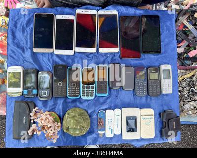 Collezione di telefoni cellulari vintage e accessori esposti su un panno blu al mercato delle pulci Foto Stock