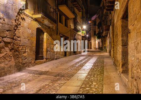 Vicolo con case in pietra medievali di notte illuminate da lampioni, Valderrobles, Teruel. Foto Stock