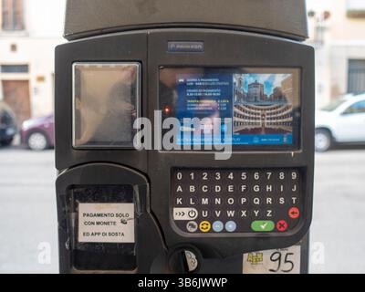Cremona, Italia - 12 aprile 2025 il moderno terminal dei parcheggi si trova su un marciapiede acciottolato a Cremona, Italia, con touchscreen a colori, Foto Stock