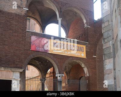 Cremona, Italia - 12 aprile 2025 facciata del Museo Diocesanocon arcate a sostegno di una bandiera che espone il nome del Museo in lingua italiana e mattone Foto Stock