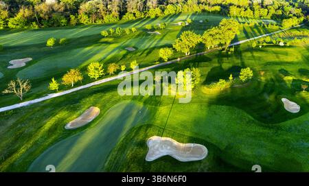 Vista aerea del tramonto sul campo da golf con alberi e laghi dai colori primaverili Foto Stock