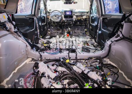 Fasci aggrovigliati di cablaggi automobilistici disordinati all'interno di un abitacolo completamente spogliato Foto Stock