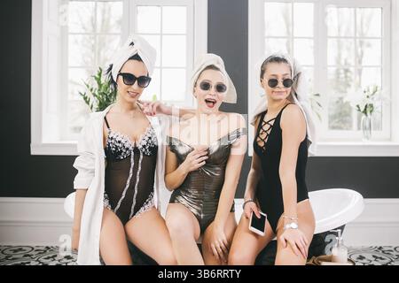 Tema amicizia femminile. Parte fidanzate, relax e trattamenti termali, gallina partito. Tre Caucasian belle donne seduti dentro il bagno in su Foto Stock