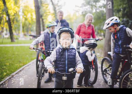 Vacanze a tema per famiglie nel parco naturale. Grande e amichevole famiglia caucasica di sei persone in mountain bike nella foresta. Figli fratelli e siste Foto Stock