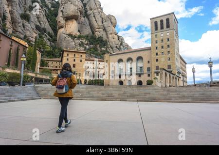 Donna turistica che cammina nel monastero di montserrat vicino a barcellona, in spagna, con le vette del massiccio del montserrat sullo sfondo Foto Stock