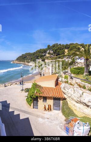 Vista panoramica del sentiero costiero cami de ronda che si snoda verso la roc de sant gaieta vicino alla comarruga, tarragona, spagna, con un'affascinante casa, palme Foto Stock