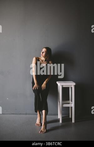 Il tema sociale della solitudine femminile è la sofferenza del dolore. Illustrazione della violenza domestica maschile. Giovane bella donna caucasica in abiti neri, Strange Foto Stock