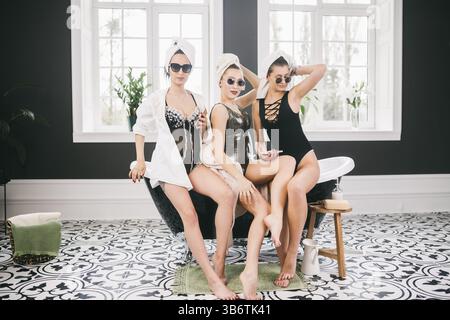 Tema amicizia femminile. Parte fidanzate, relax e trattamenti termali, gallina partito. Tre Caucasian belle donne seduti dentro il bagno in su Foto Stock