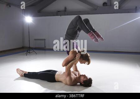 Il tema di Acroyoga e Yoga pone. Acroyogis praticante. con studio di retroilluminazione. La base uomo detiene la statica pone una donna Flyer in cima abo Foto Stock