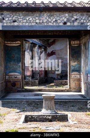 Rovine di un'antica villa romana con mura affrescate e una colonna in pietra in primo piano. La struttura presenta i resti di decorazioni dipinte e S Foto Stock