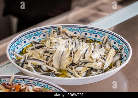 Acciughe marinate con aceto, olio d'oliva, pepe e prezzemolo, in un piatto di ceramica decorato, primo piano Foto Stock