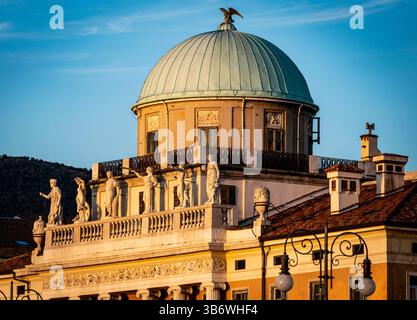 Una vista ravvicinata di un edificio storico caratterizzato da una cupola con un tetto di rame verde e statue lungo il tetto. L'edificio è illuminato da un caldo su Foto Stock