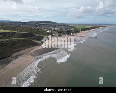 Veduta aerea di Saltburn Beach, North Yorkshire, che cattura una lunga passeggiata sulla spiaggia con onde dolci e cieli nuvolosi, un luogo popolare per passeggiare con i cani. Foto Stock