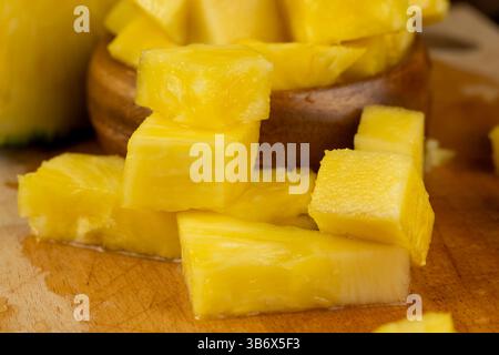 ananas giallo maturo a fette, un gran numero di pezzi di ananas maturo affettato a pezzi durante la cottura, primo piano Foto Stock