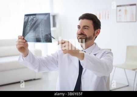 Medico sorridente che esamina la scansione RM del collo in clinica Foto Stock