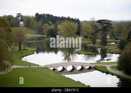 Elegante giardino paesaggistico con ponte in pietra, lago e padiglione nella campagna inglese. Painshill, Cobham, Inghilterra Foto Stock