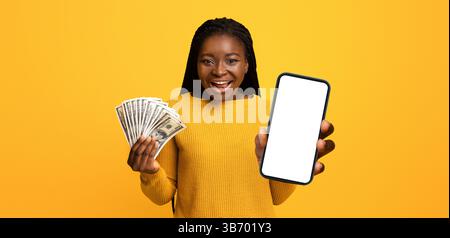 Concetto di cashback. La giovane donna eccitata che tiene in mano smartphone e Dollar Cash, ha ricevuto un bonus di grande denaro, esclamando con Joy, celebrando il successo, Standing Foto Stock