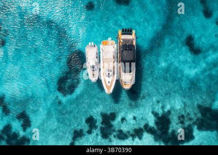 Vista aerea di tre yacht su acque azzurre trasparenti Foto Stock