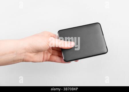 Uomo con disco rigido esterno su sfondo grigio chiaro, primo piano Foto Stock