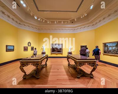 Galleria d'Arte dell'Ontario, sala espositiva interna a Toronto, Canada, con persone che osservano dipinti e sculture su pareti gialle, con tavoli ornati Foto Stock